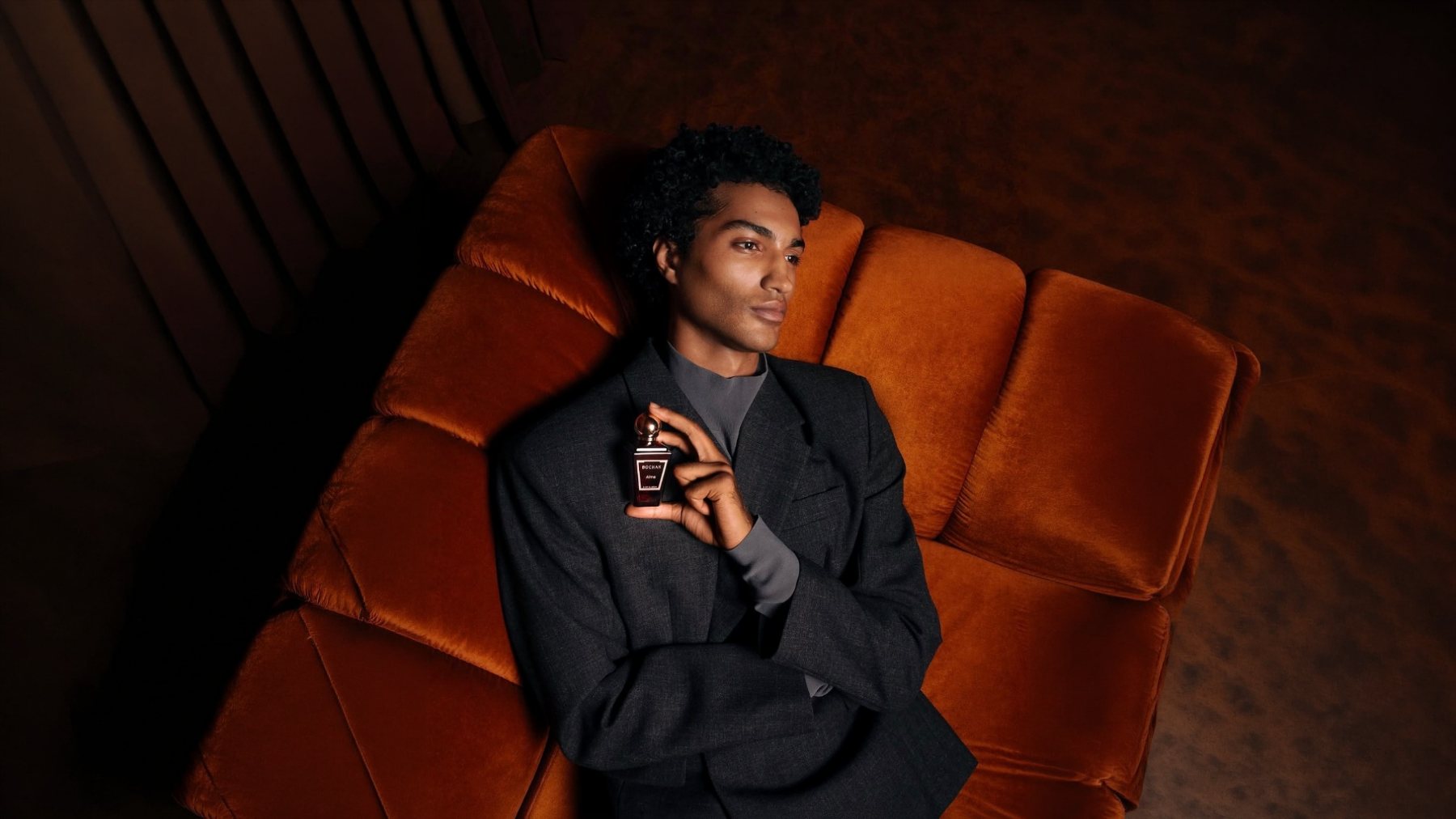 BOCHAN fragrance campaign New York: model on an orange velvet sofa with the bottle