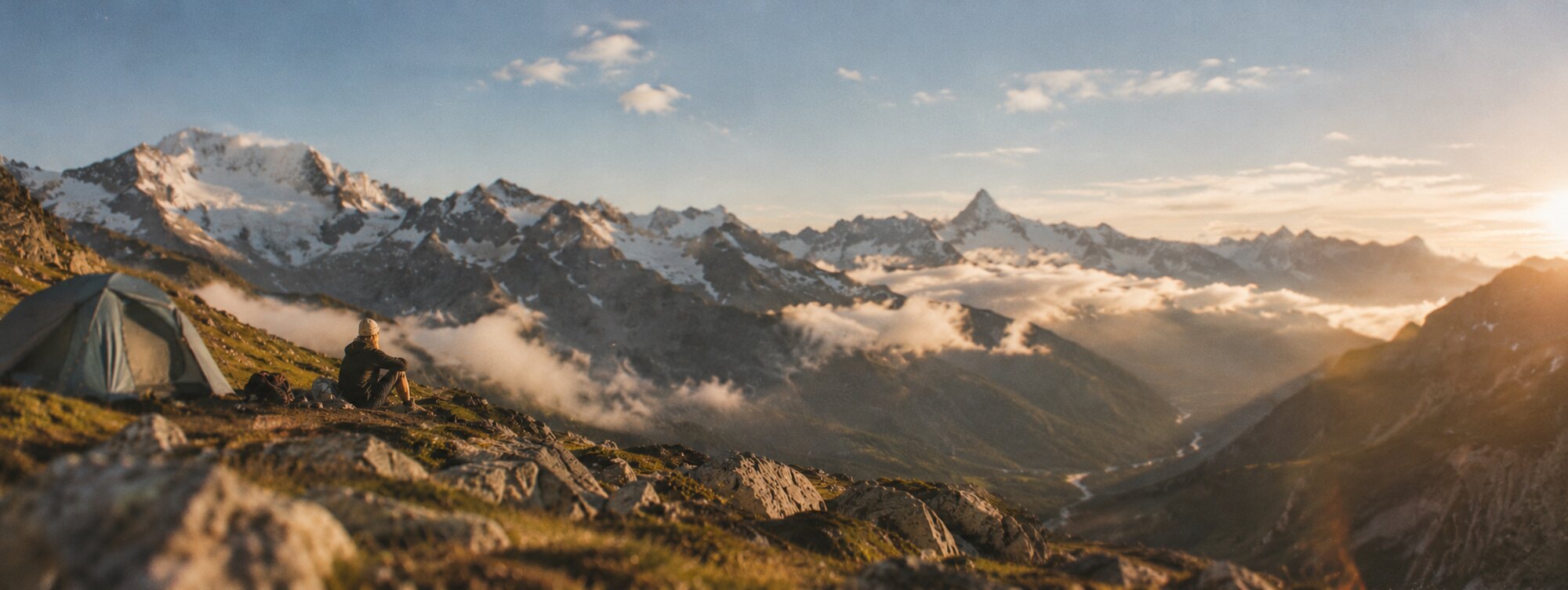HIKING CLUB: Panorama mit Zelt und Wanderer bei Sonnenuntergang in einem Alpental